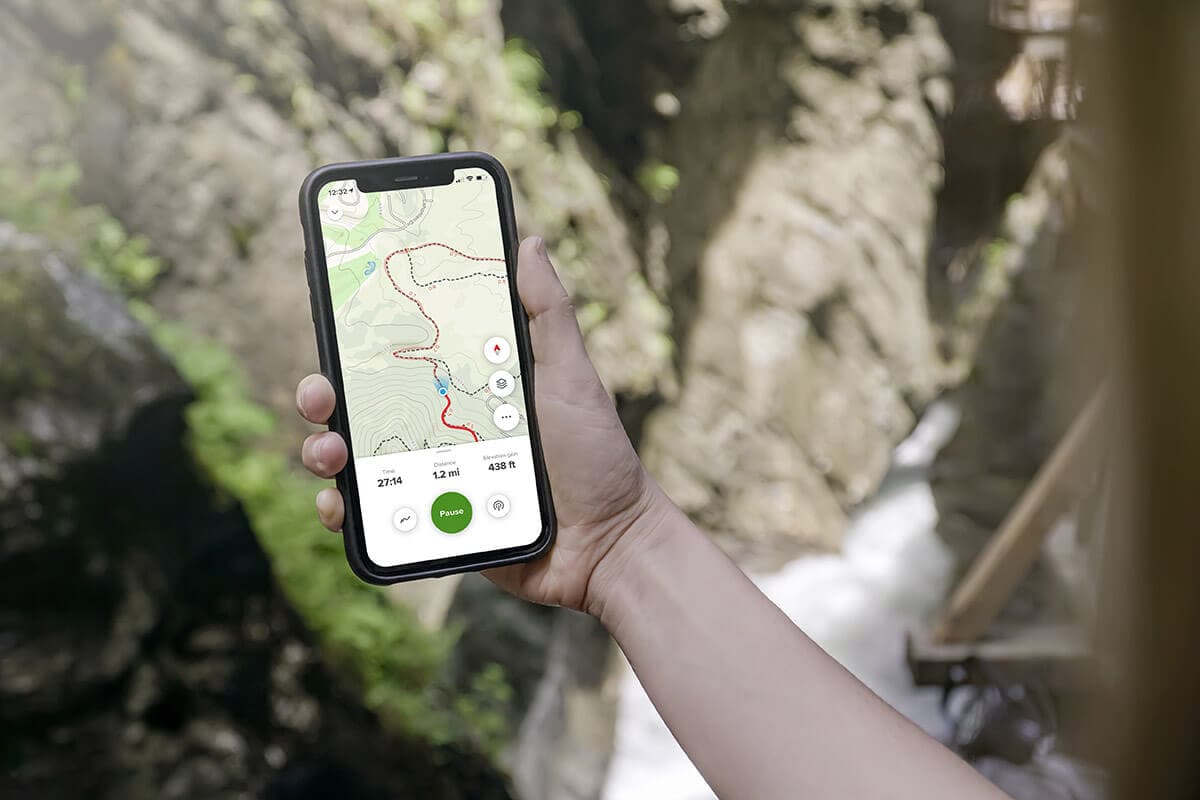 Photo of a hand holding a cell phone with AllTrails+ on the screen