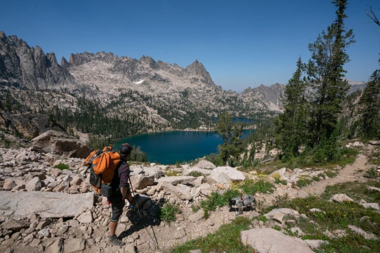 Backpacker stopped on trail to look out over alpine lake view in the Sawtooth Mountains on a backpacking trip to Baron Lake