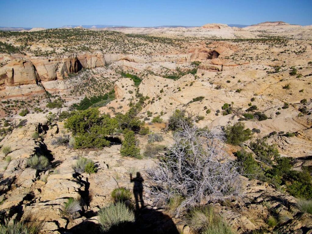 Silhouette of hiker standing on overlook with views out onto Utah slickrock landscape