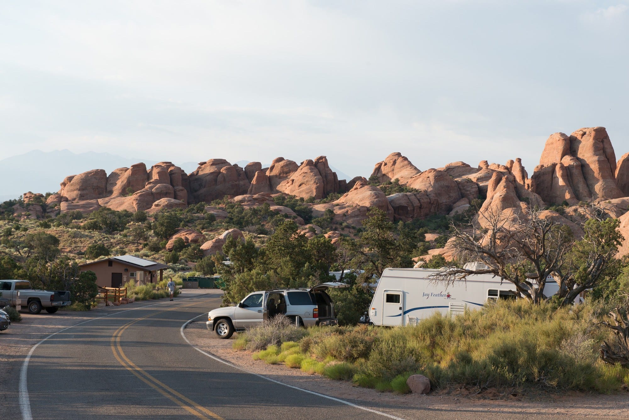Devils Garden Campground in Arches National Park with red rocks in the background and a silver vehicle pulling a camper