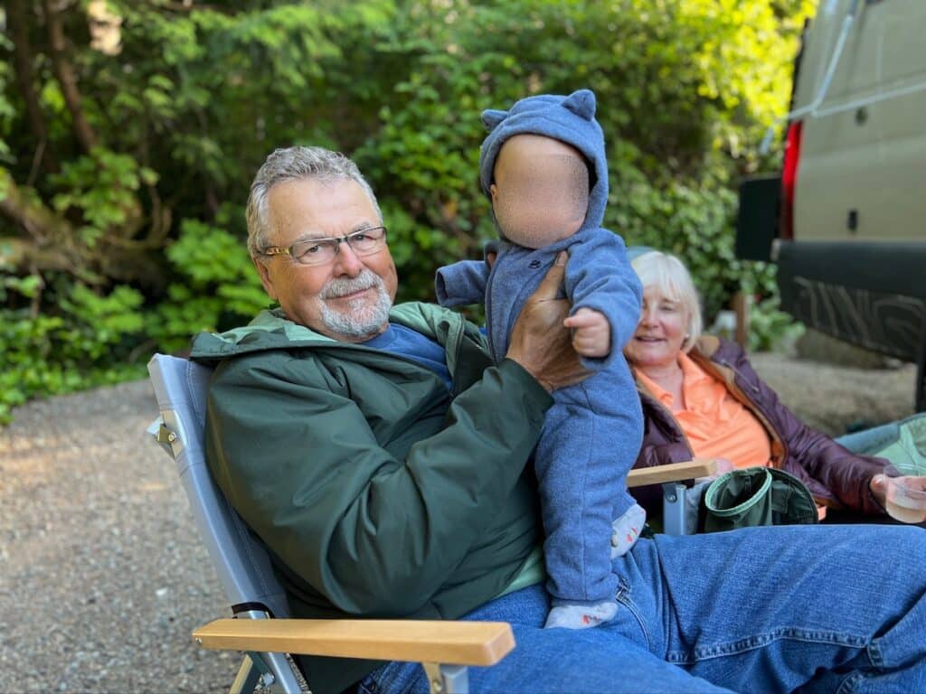 Grandpa holding baby in a camp chair at a campground