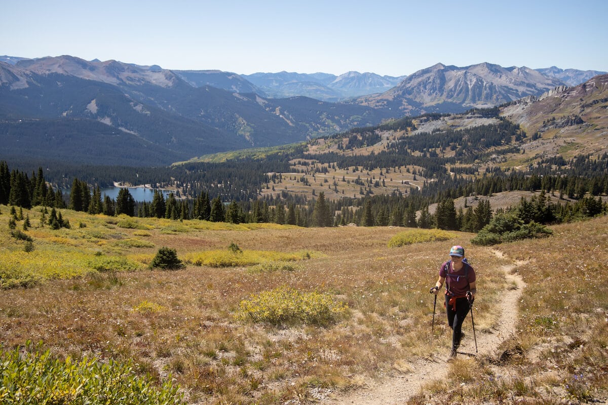 Woman hiking on a dirt trail in Colorado with low mountains in the background