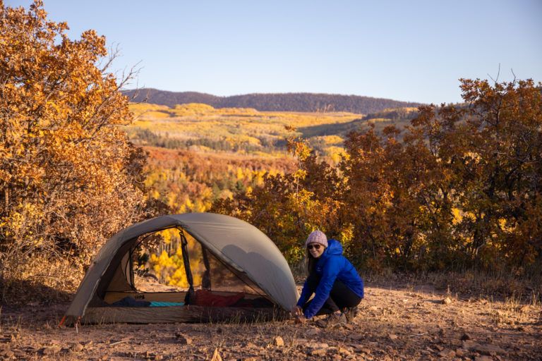 Kristen Bor setting up a tent at a lookout surrounded by fall colors