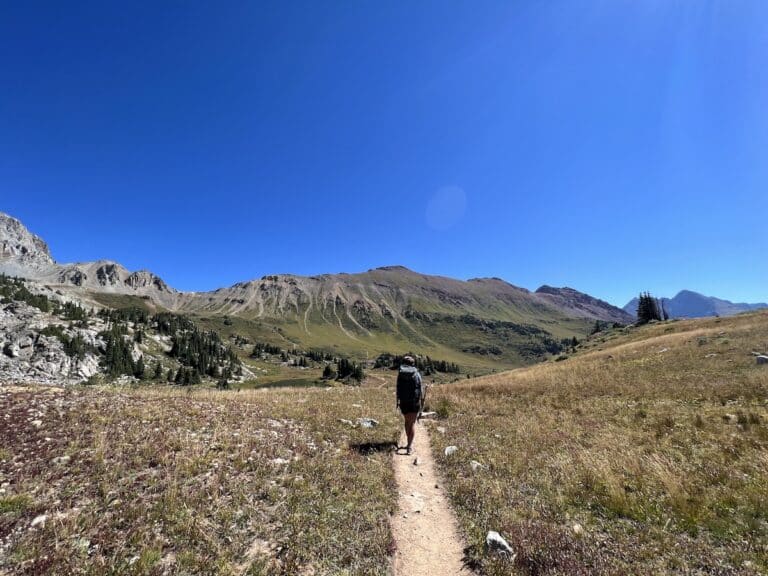 Hiker on the Four Pass Loop trail with mountains in the distance.