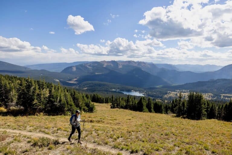 Woman hiking through dry meadow on high alpine hike in Colorado