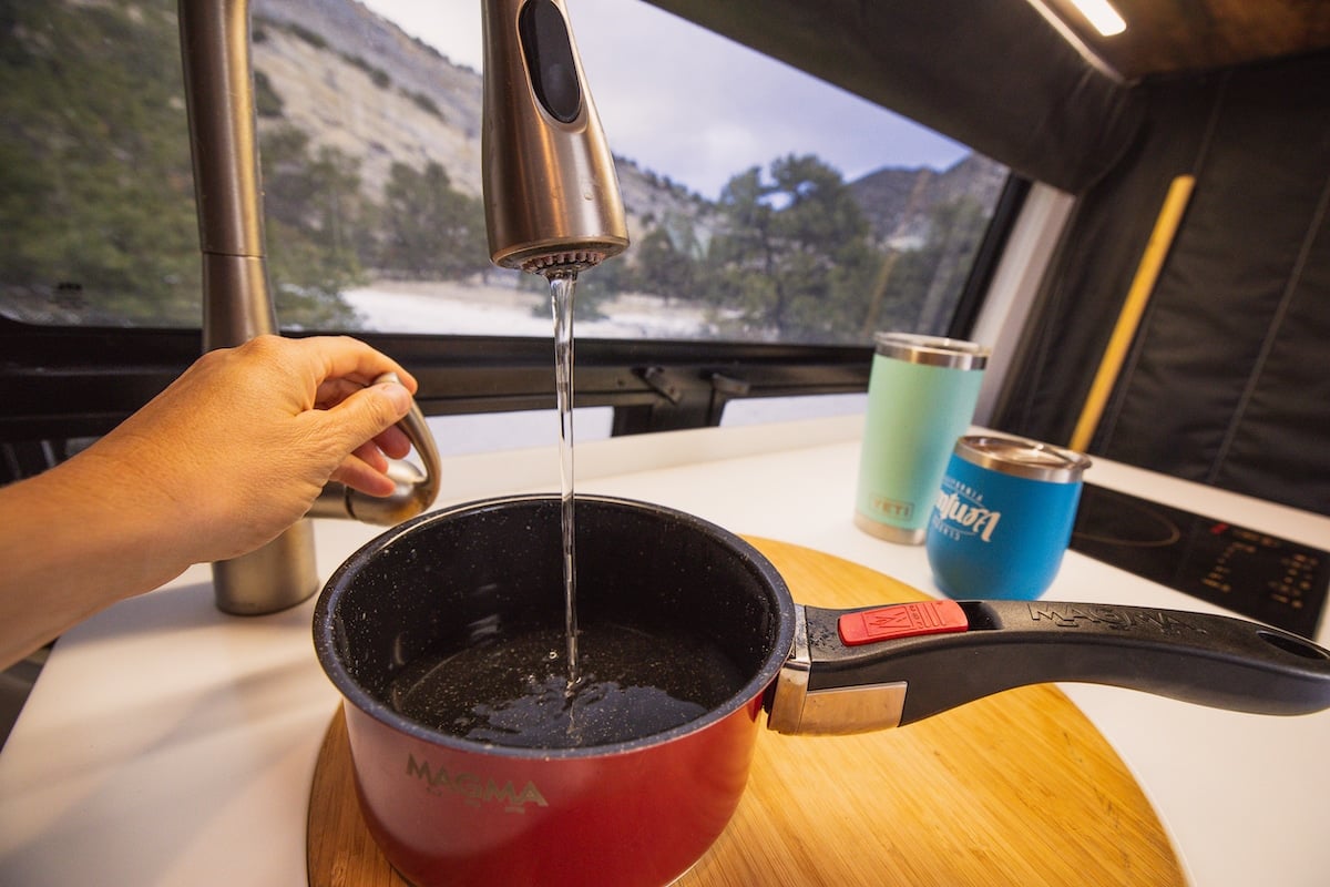 Water from a faucet going into a red pan in a camper van