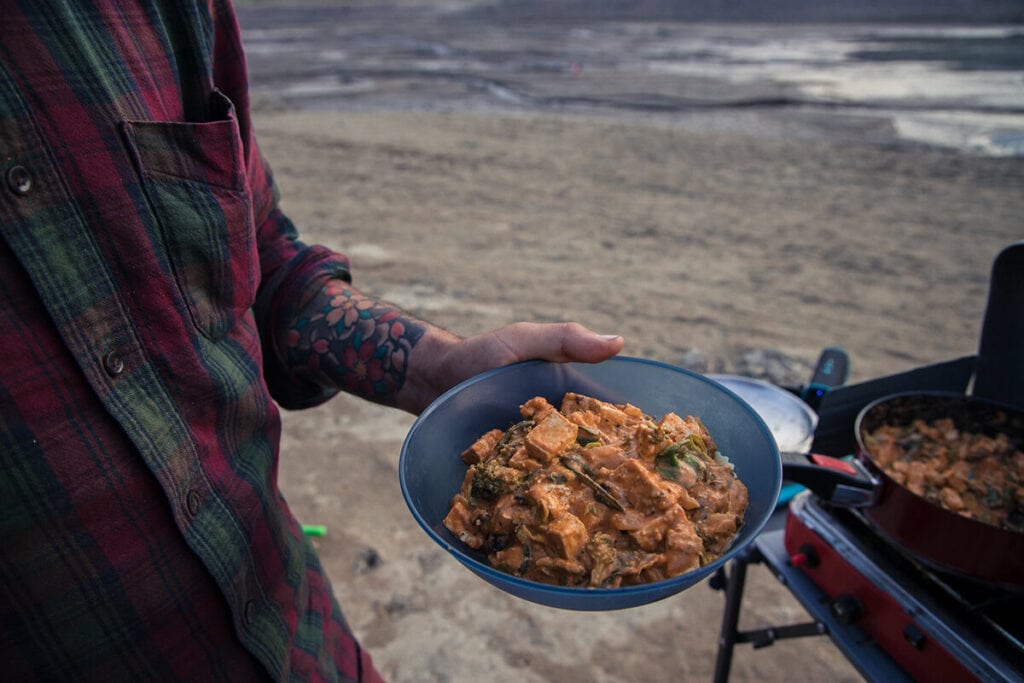 A man holds up a bowl of curry in the GSI Infinity Bowl