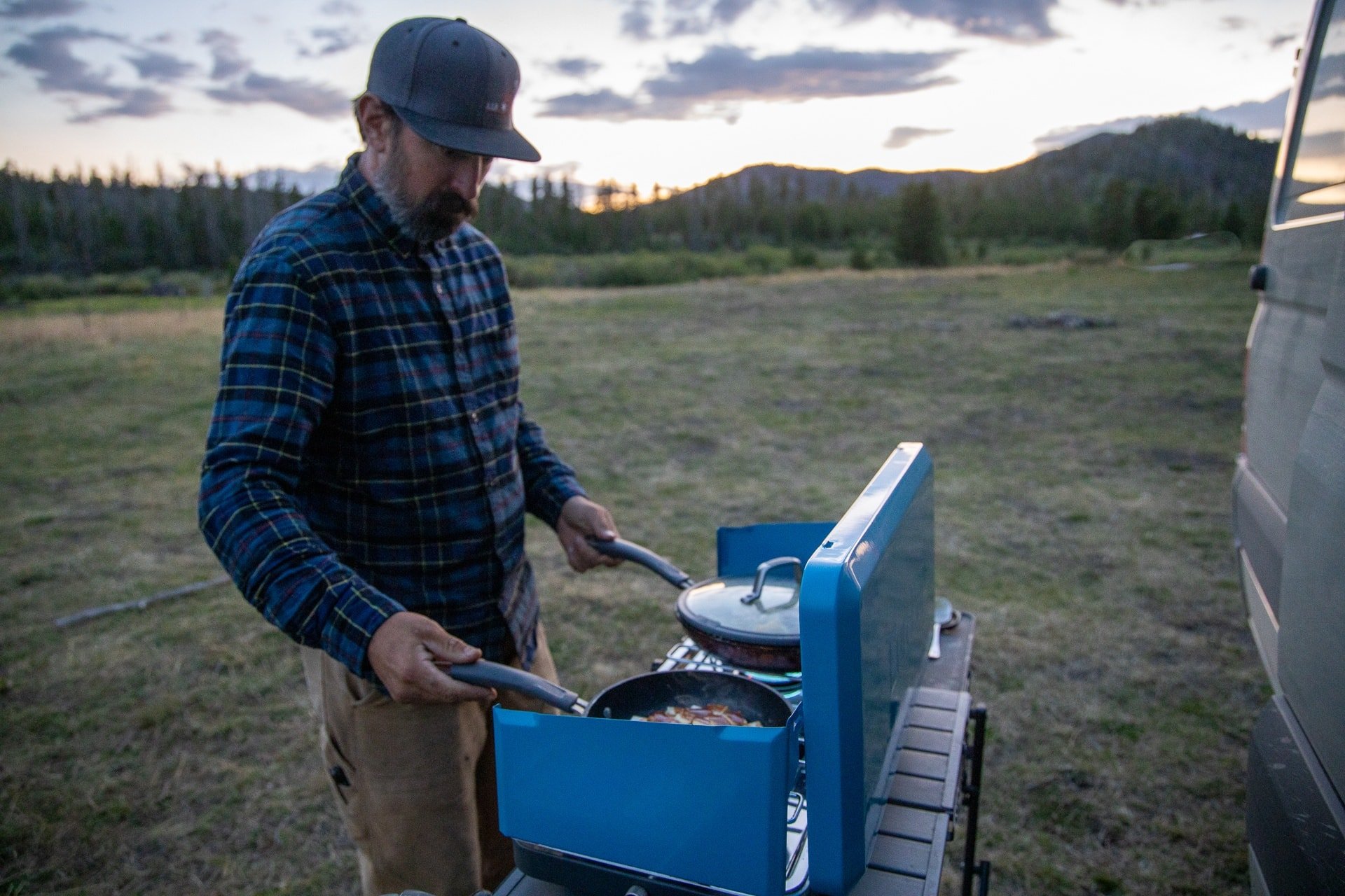 A man cooks on a camping trip using the Eureka XL Camp Stove