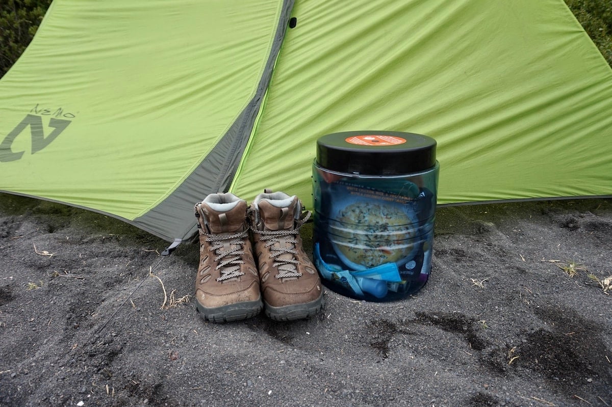 Pair of hiking shoes and a bear canister outside of tent