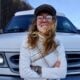 Bearfoot Theory content coordinator Courtney standing in front of her white Chevy camper van