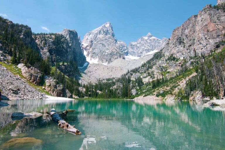 Delta Lake in Grand Teton National Park surrounded by tall peaks with patches of snow