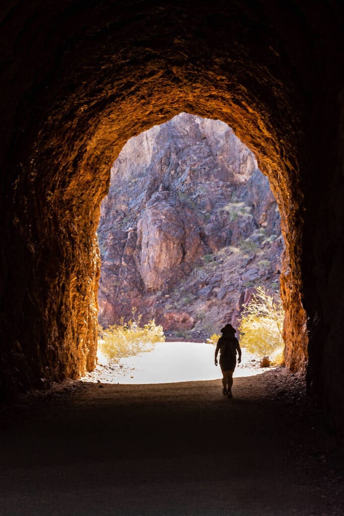 Hiker walking through opening of tunnel along the Hoover Dam Historic Railroad Trail near Boulder City, Nevada