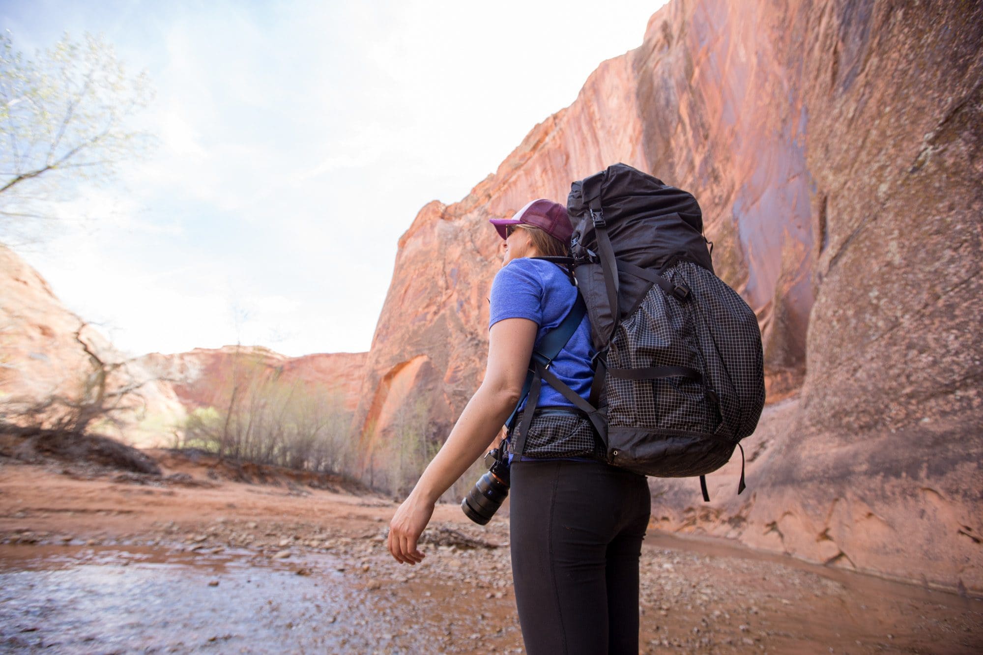 Kristen Bor wearing a Hyperlite backpacking pack looks up at a red rock canyon while backpacking in Utah