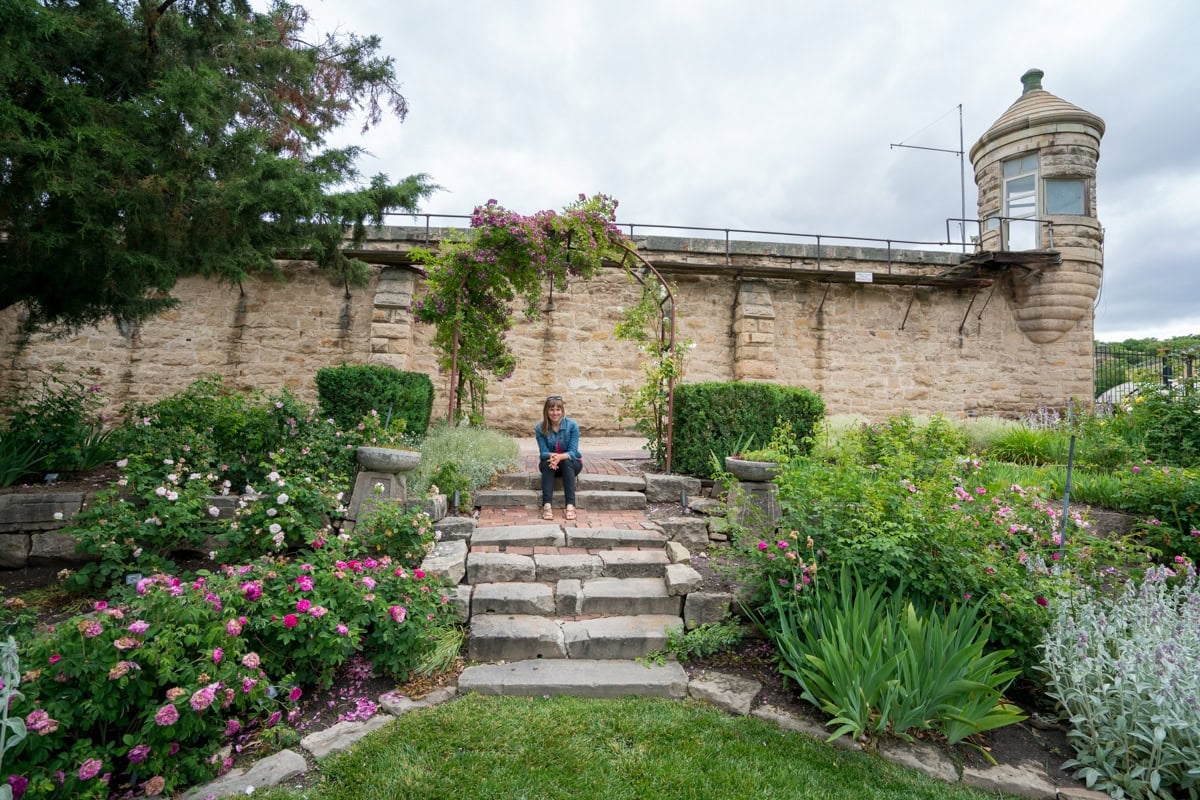 Kristen Bor sitting on steps in the Idaho Botanical Garden with the old Idaho Penitentiary in the background