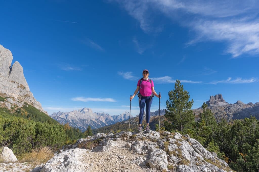 Kristen Bor hiking in Italy near Cortina-d-Ampezzo wearing blue lululemon Wundertrain leggings and a pink shirt wirth mountains in the background