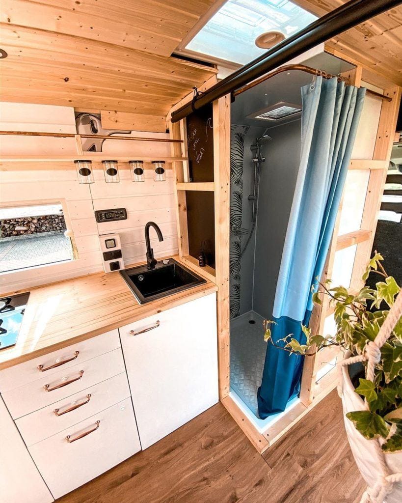 Camper van bathroom setup with indoor shower and portable toilet by @makai.the.van