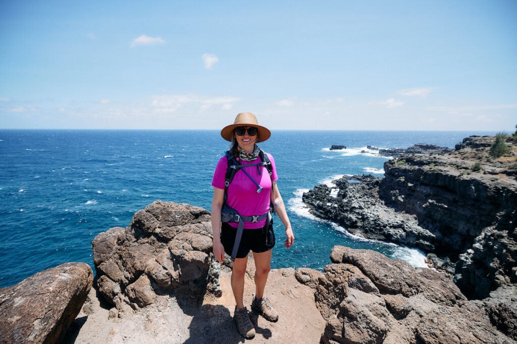 Woman stands on the coast of Maui on the Acid War Zone Trail. She's wearing The North Face Aphrodite shorts