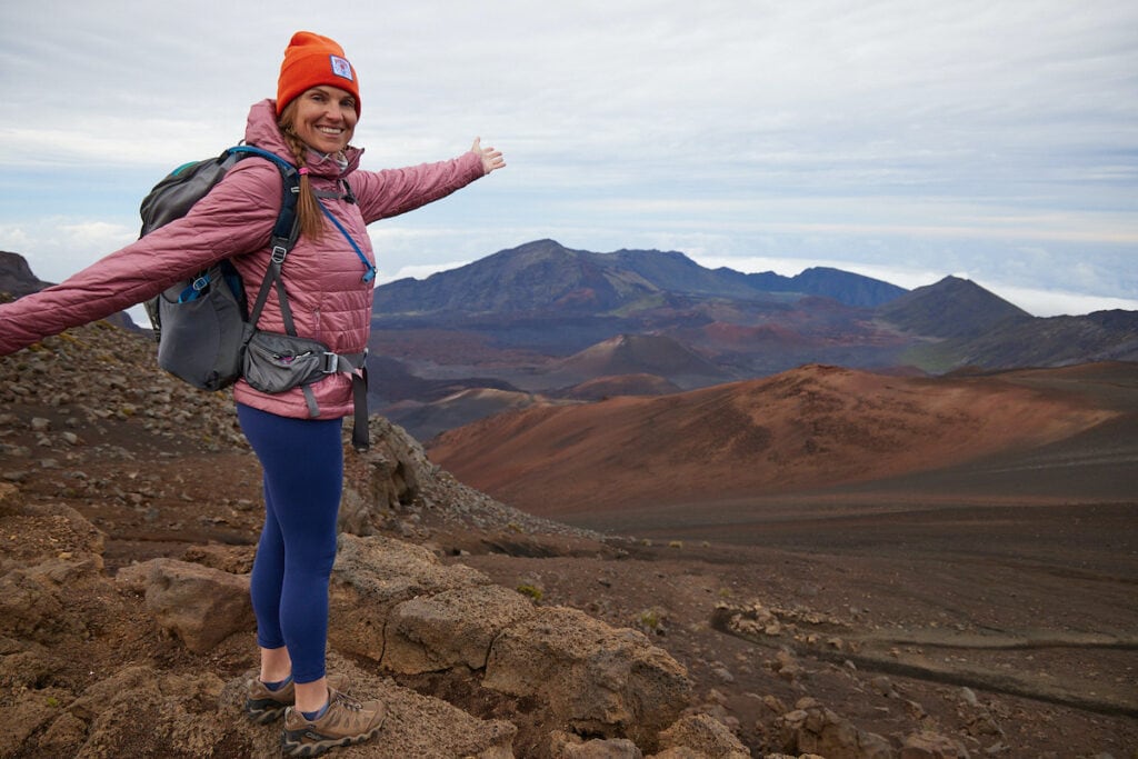 Kristen smiling for phot with arms stretched out wide on a hike in high-alpine area of Colorado