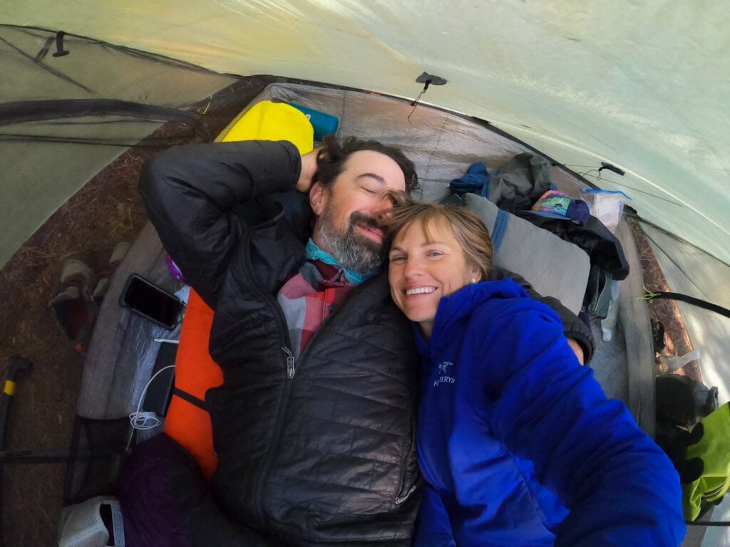 A woman and man smile at the camera in their Triplex tent