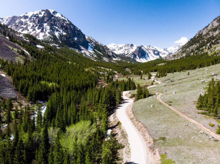 Road cutting through valley in Montana with tall peaks on either side