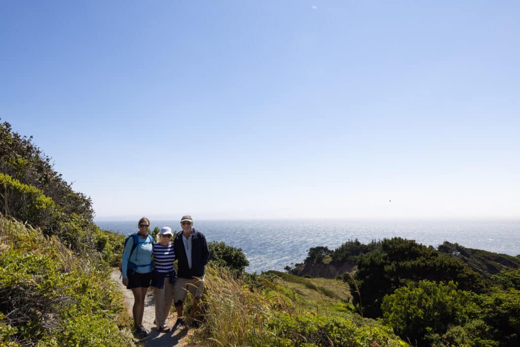 Three people on a hiking trail on a sunny day o the Oregon coast