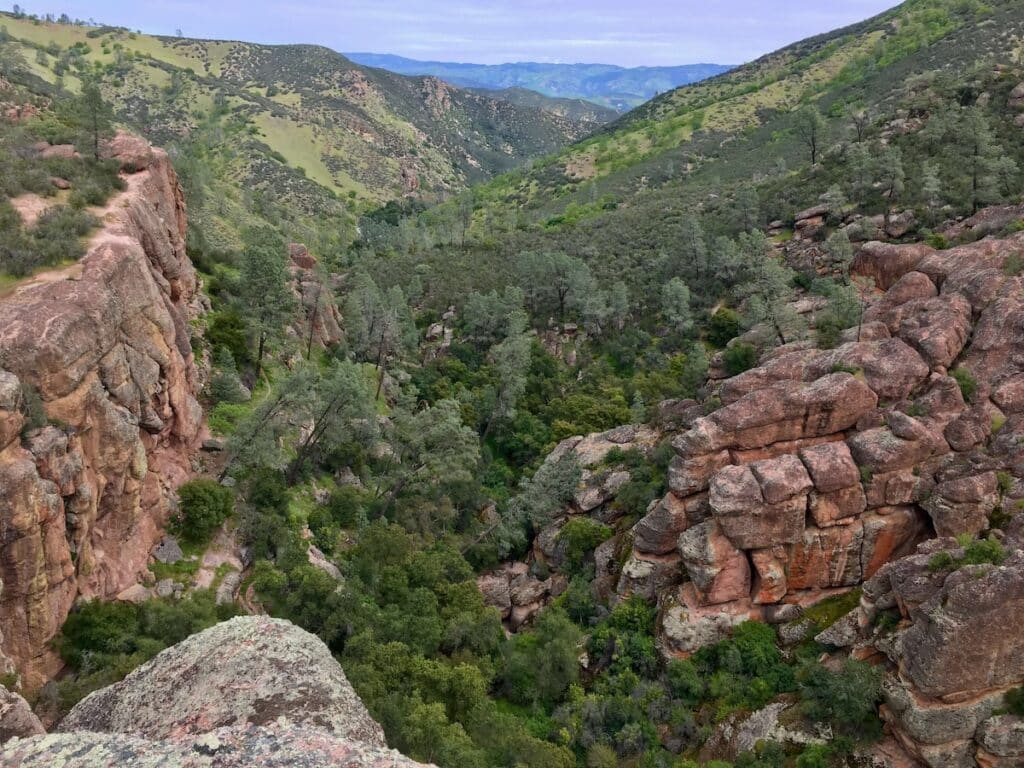 Landscape photo of Pinnacles National Park with green forests and large red boulders