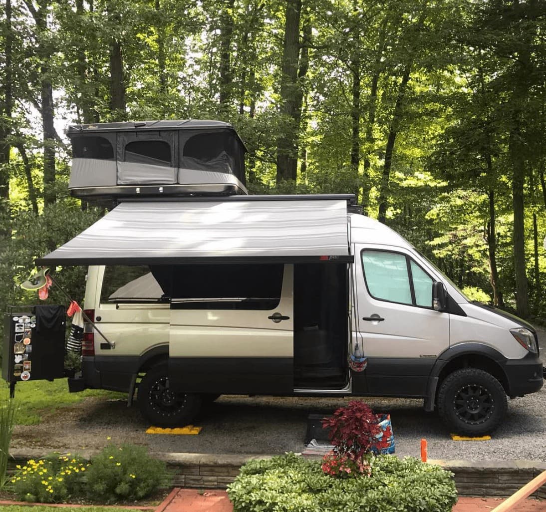 Sprinter van with a popped rooftop tent and awning