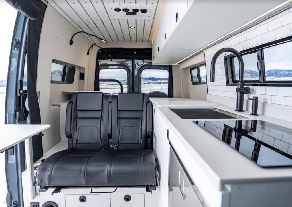 Sprinter Van converted by Rossmonster. Photo shows a bench seat next to a galley