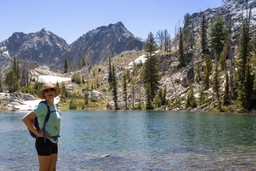Woman standing next to alpine Sawtooth Lake in Idaho