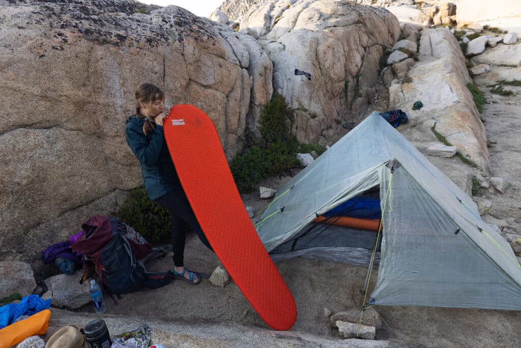 Kristen Bor blowing up a Thermarest Sleeping Pad next to her ZPacks Triplex tent in Sequoia National Park