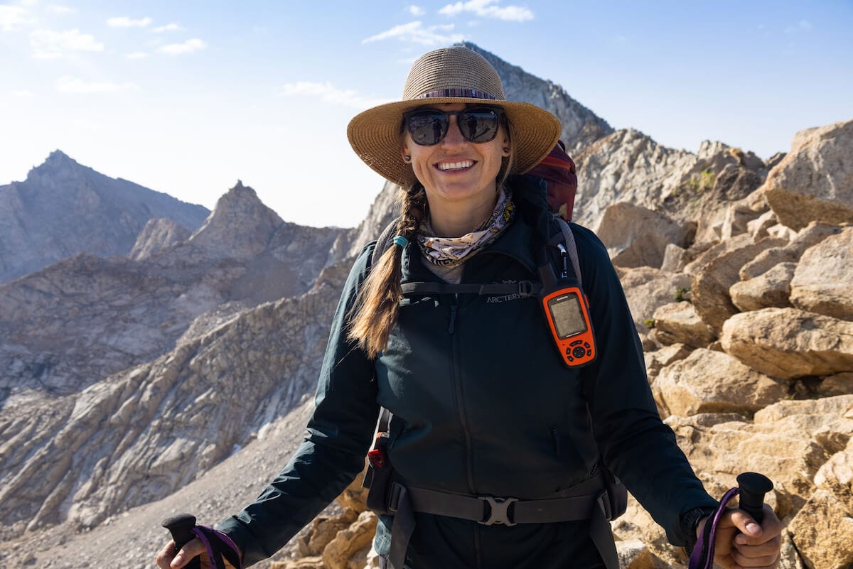 Kristen Bor smiles directly at the camera while holding trekking poles and wearing a backpacking pack. She's on the Mineral King Loop Trail in Sequoia National Park.