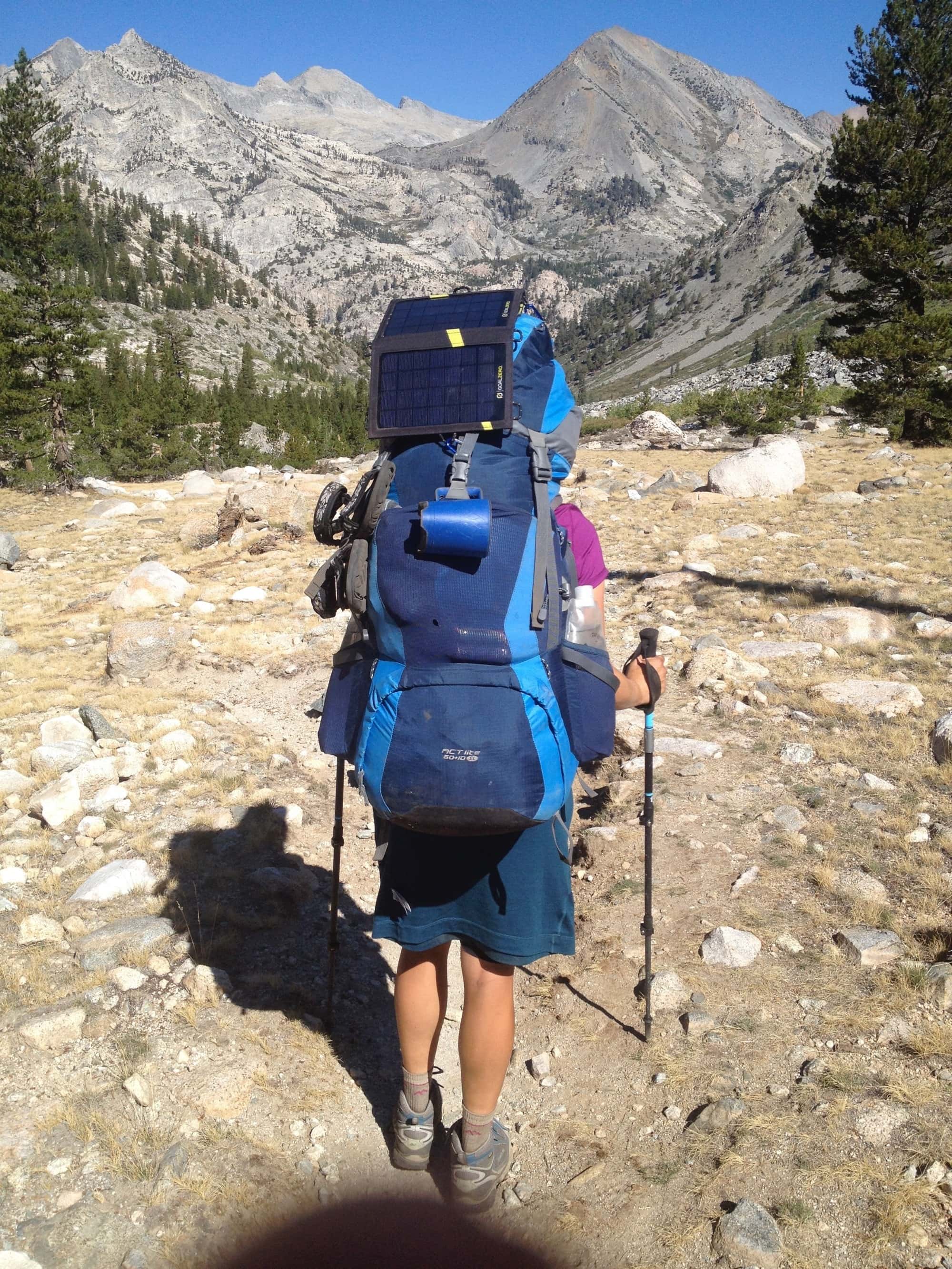 Kristen Bor wearing a large backpacking pack on the John Muir Trail. There's a solar panel hanging off the pack
