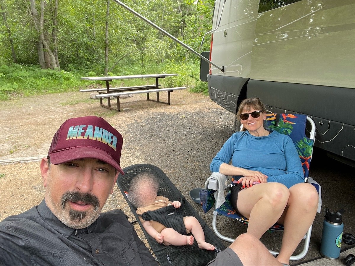 Kristen Bor with her partner and baby sitting in chairs outside of a Sprinter van