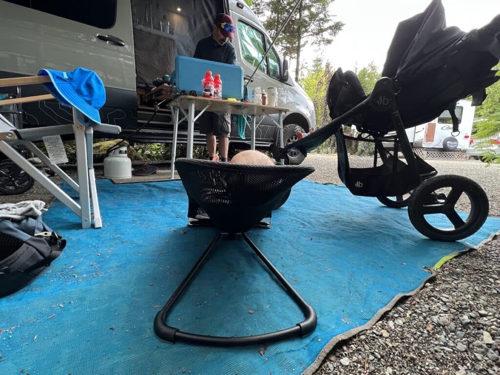 Baby in bouncer at campsite next to a Sprinter Van