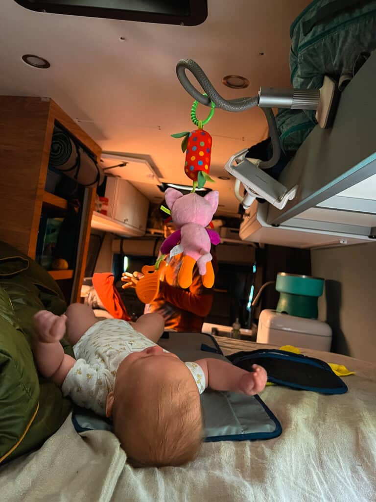 Baby on bed in Sprinter Van with toys