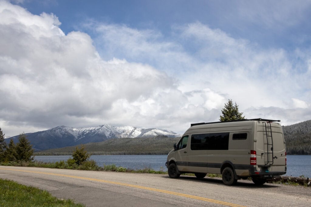 Sprinter Van parked on the shore of Alturas Lake in Stanley idaho with snowcapped mountains in the distance