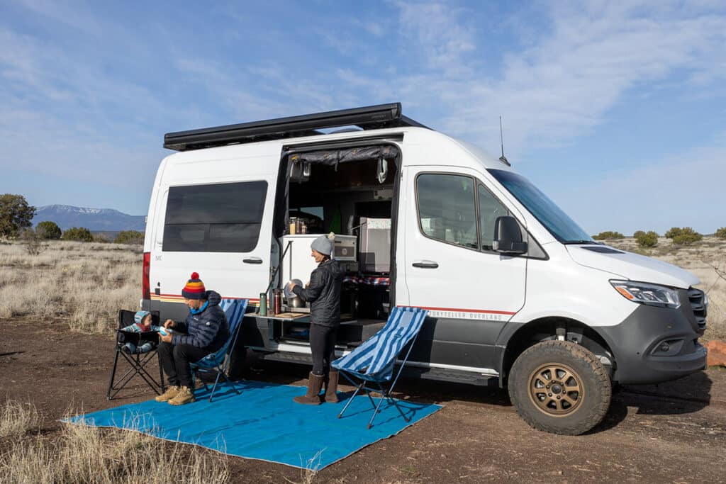 Family with a baby cooking outside of a Storyteller Overland campervan near Sedona, AZ