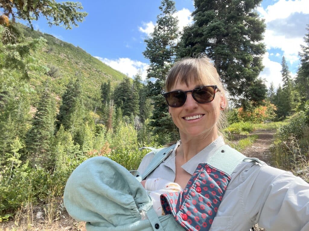 Kristen Bor hiking with baby in baby carrier in park city utah wearing the Roka Rory 2.0 sunglasses