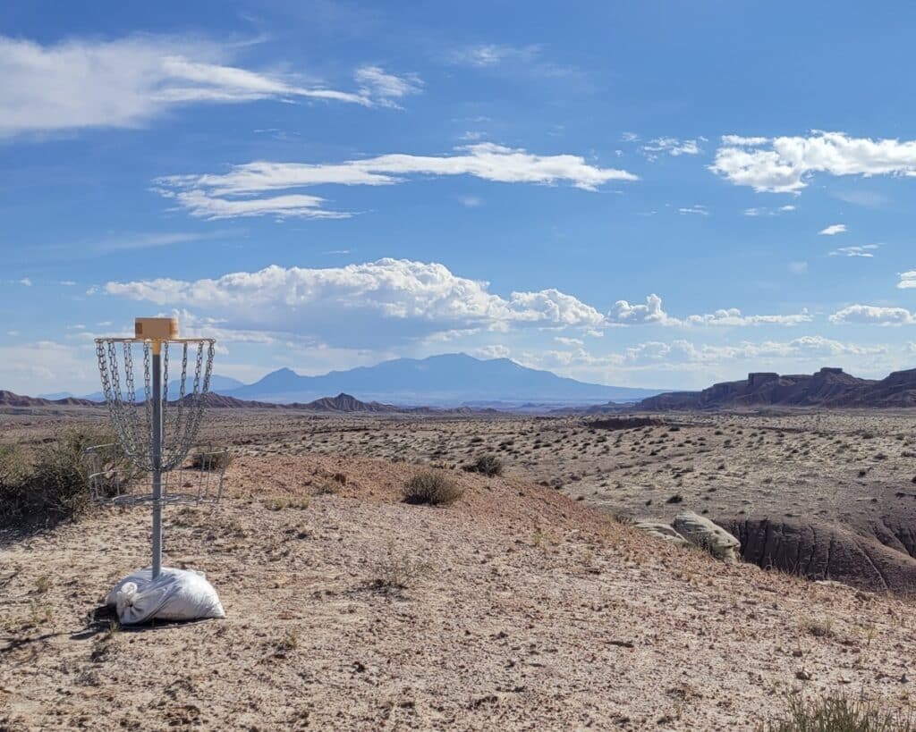 Disc golf hole with mountains in the background at Goblin Valley State Park in Utah