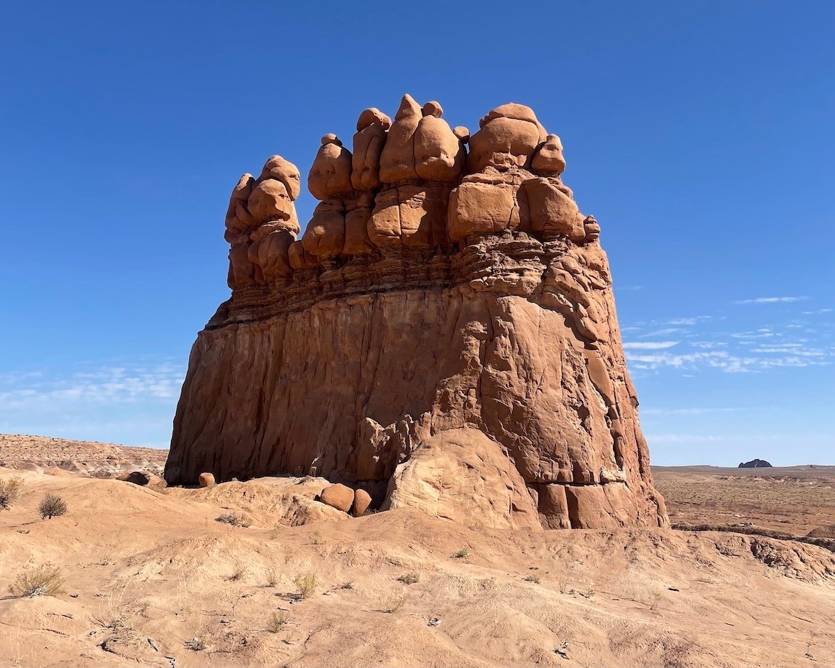 An orange rock formation against a blue sky in Goblin Valley State Park in Utah