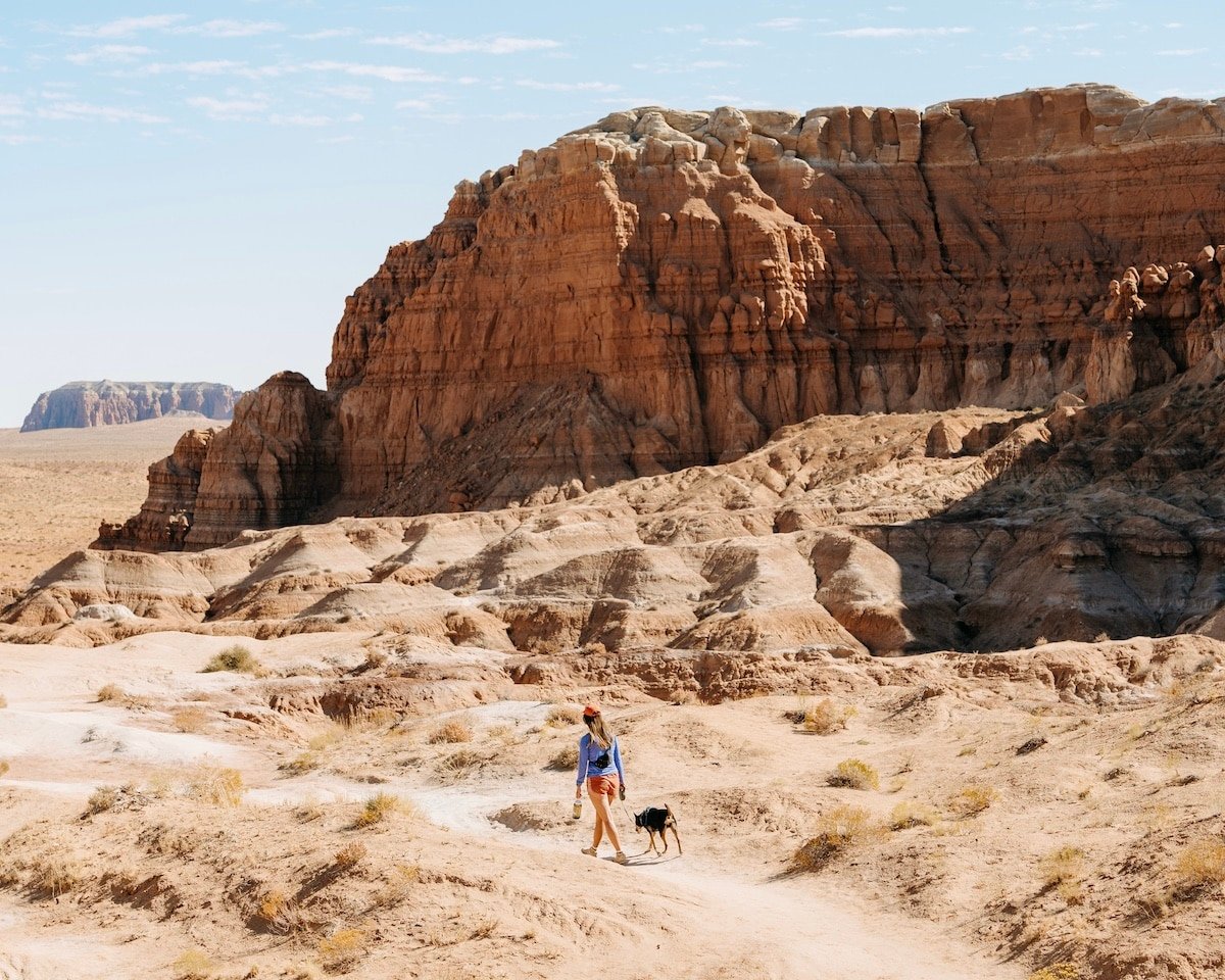 Female hiker with a dog on the Goblin's Lair trail in Goblin Valley State Park in Utah