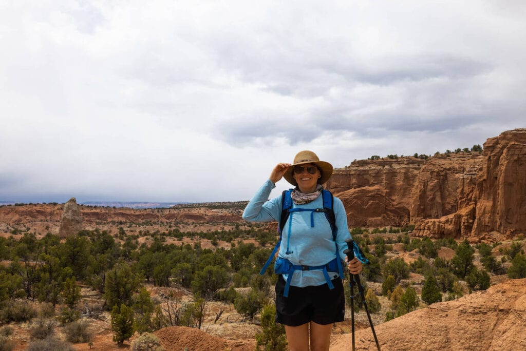 Bearfoot Theory founder Kristen Bor hiking in Kodachrome Basin with red cliffs behind her