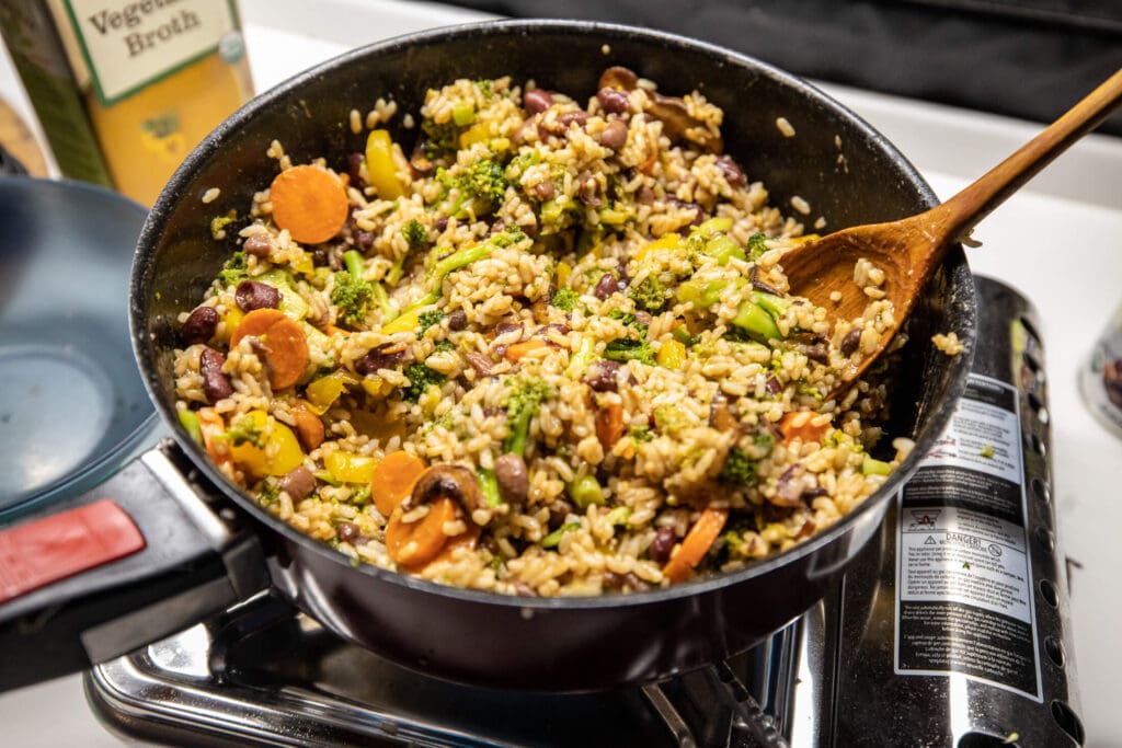 Close up of a one-pot meal in a campervan with vegetables, sweet potato, and rice