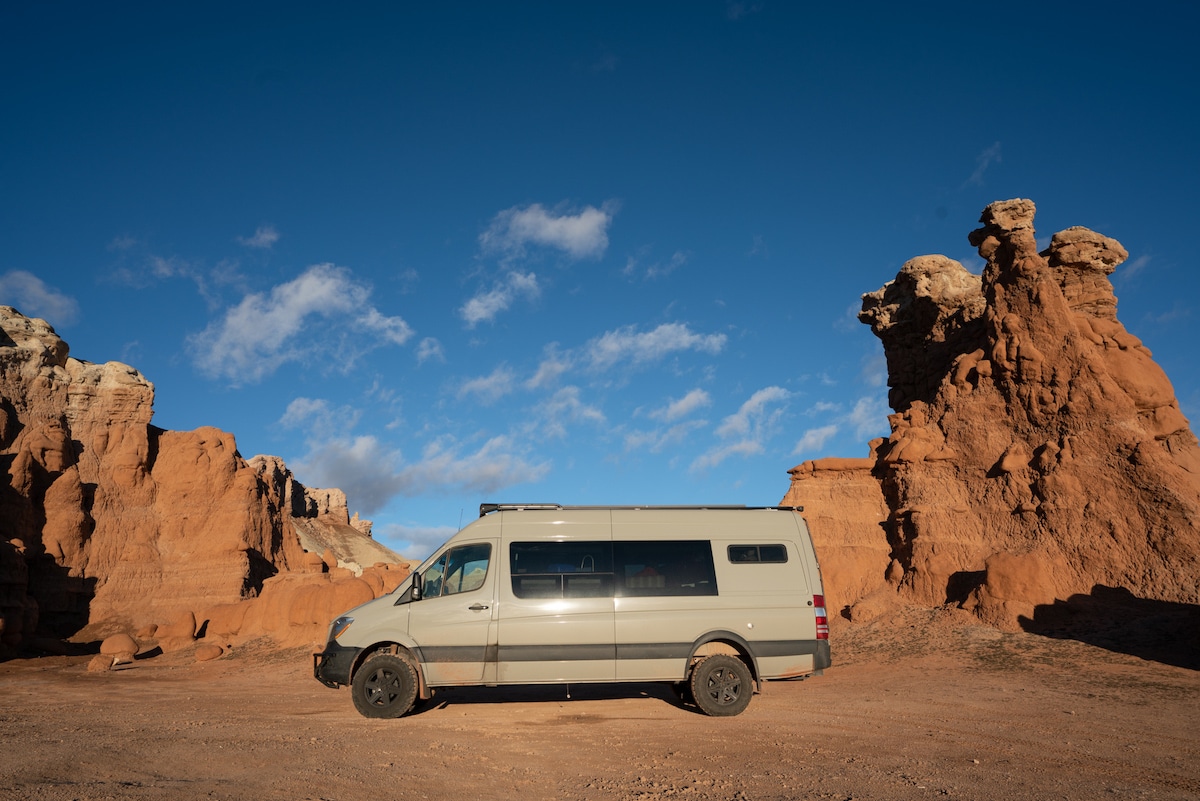Sprinter Van between orange rocks on BLM outside of Goblin Valley State Park in Utah