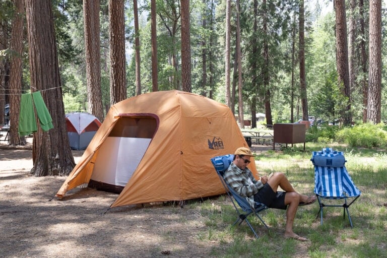 Man sitting in a camp chair in Yosemite next to a REI tent